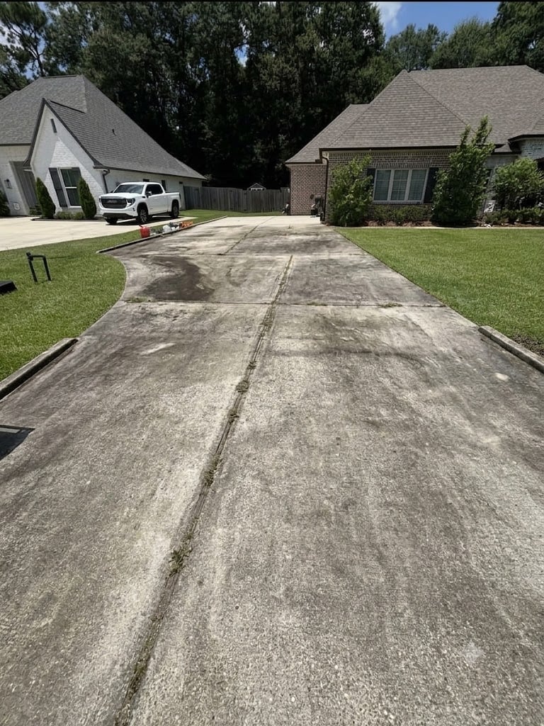 After - Wide driveway with visible wear and cracks leading to two residential houses with brick exteriors and manicured lawns